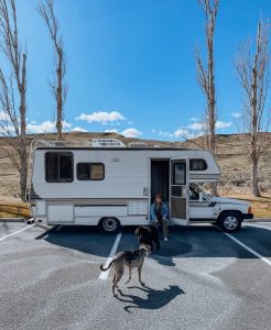 owner with dog and RV outside in nature